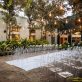 Decorated ceremonial area outdoors with modern transparent chairs and beautiful festoon with lots of trees and plants