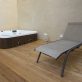 Jacuzzi and deck chair on wooden floor in a house.