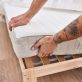 Young man holding mattress at bedroom