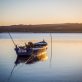 An old fishing boat at the river with the breathtaking view of the sunset in the background